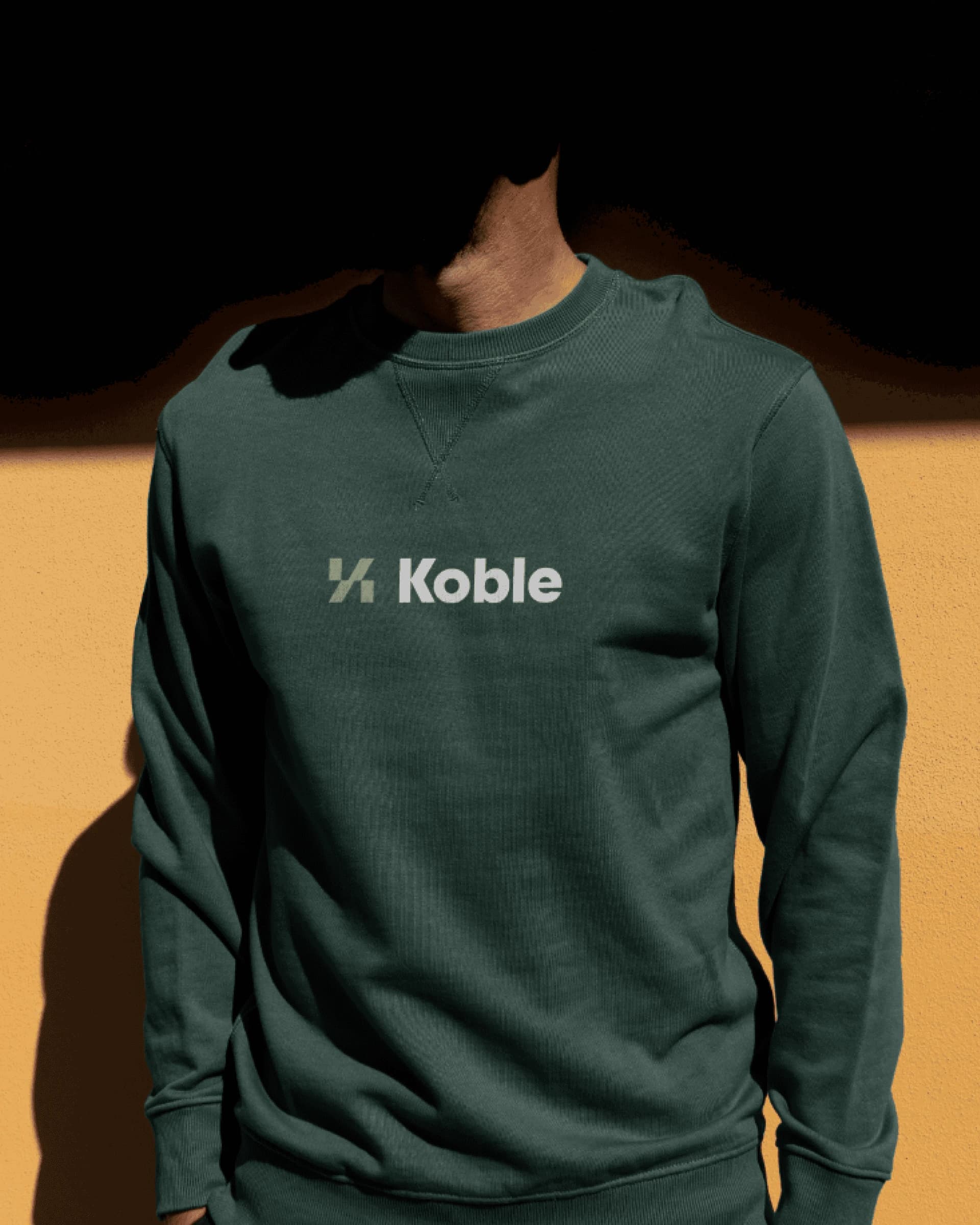 Forest green sweatshirt with the Koble logo.